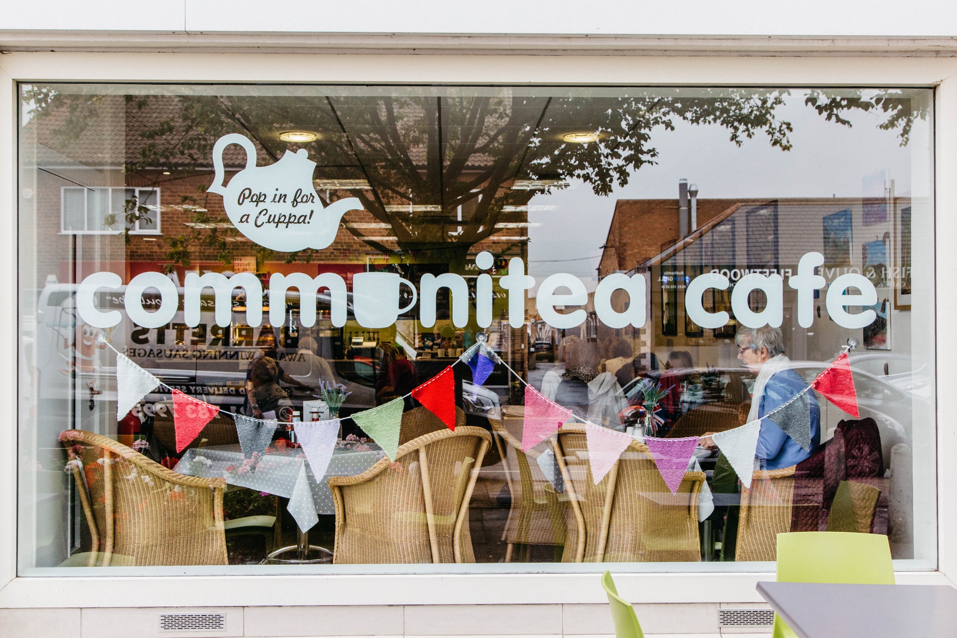The Communitea Café window with bunting and customers inside.