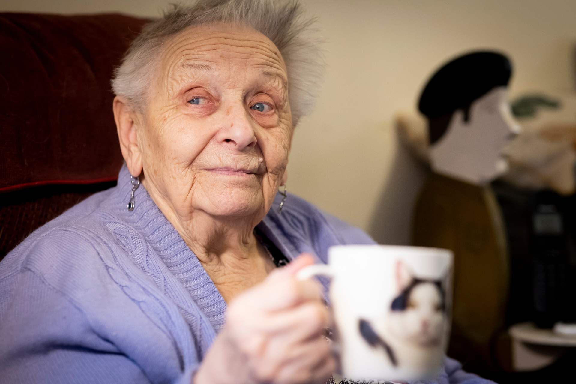 Older woman sitting comfortably at home holding a mug