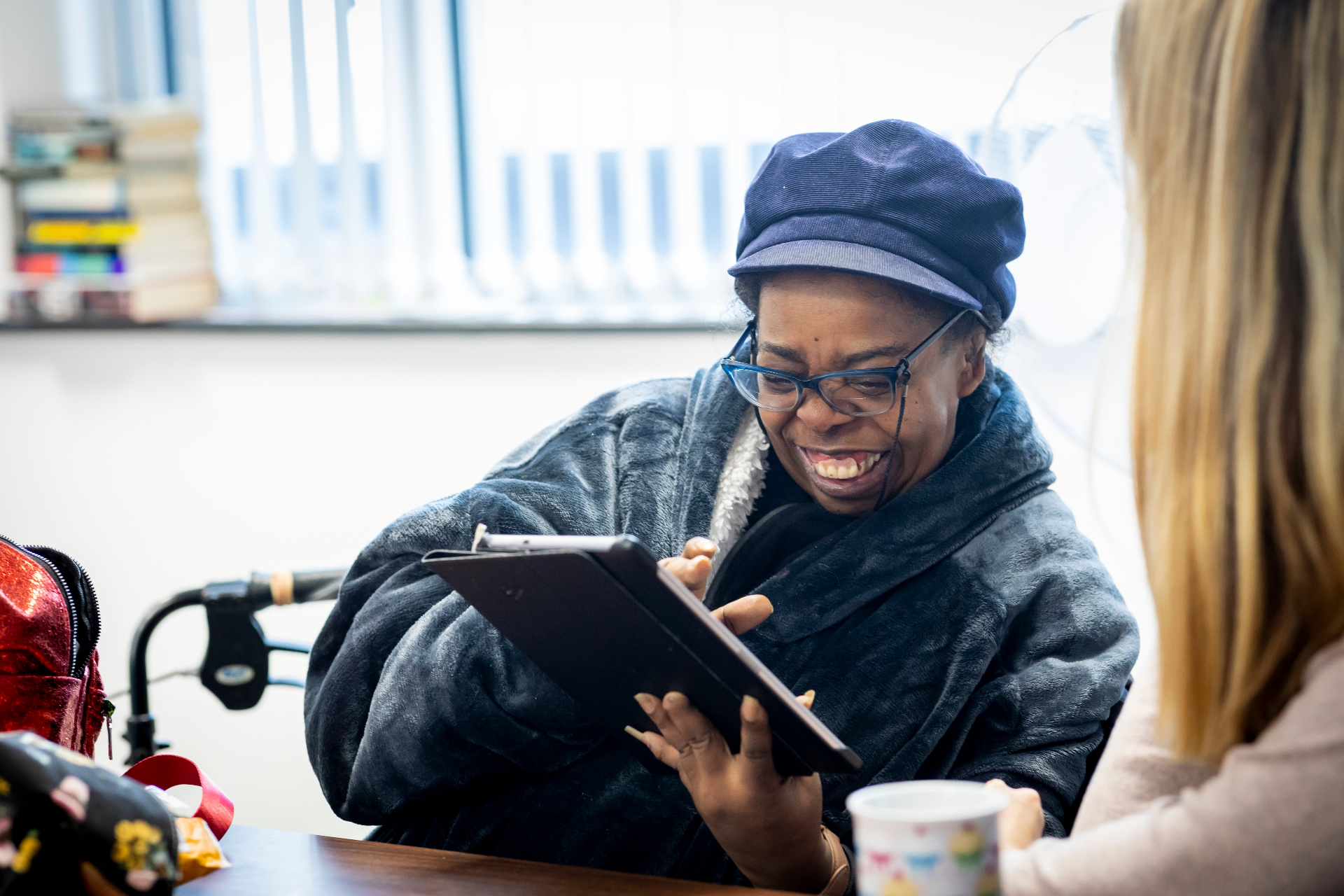 Woman laughing while using a tablet with a support worker