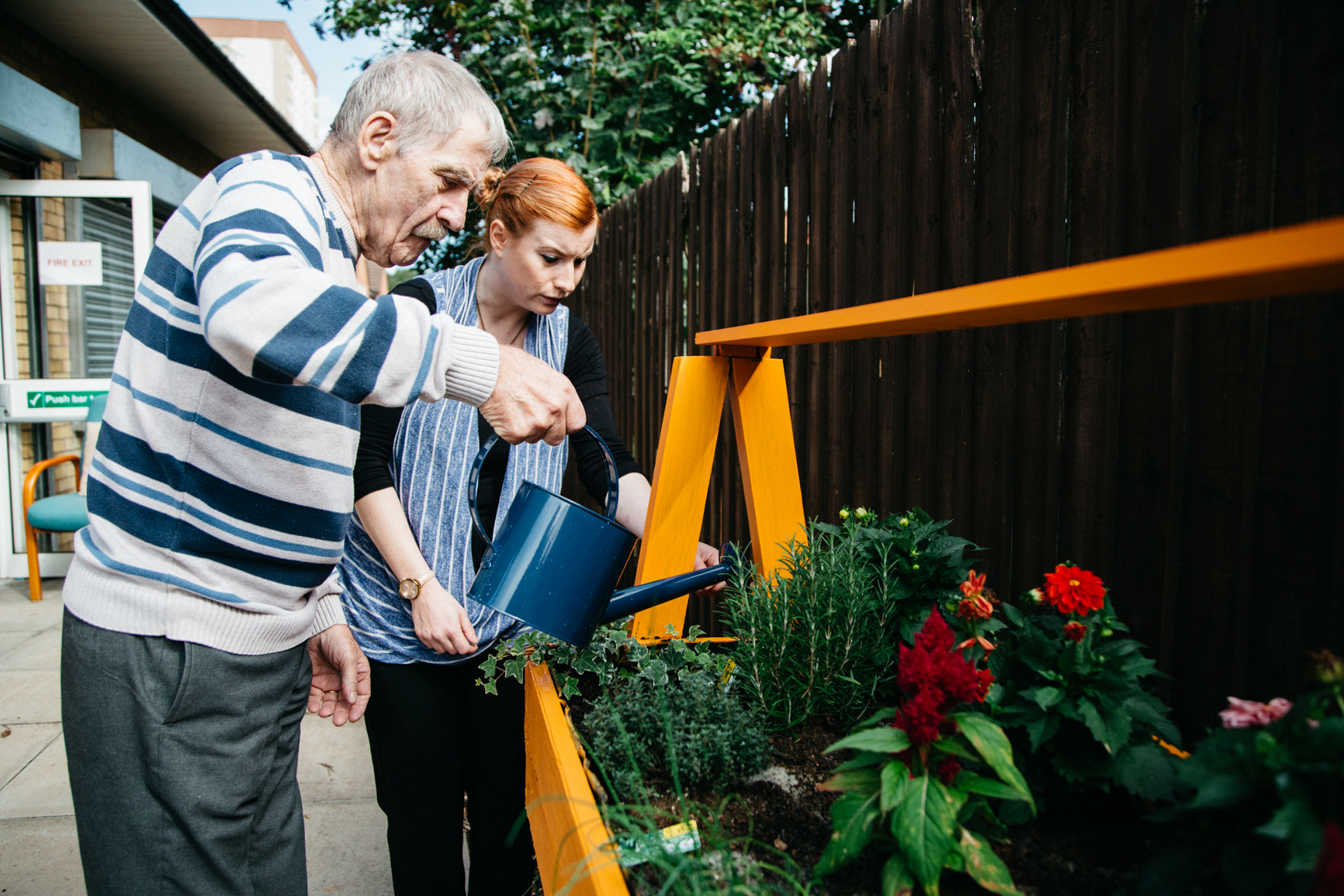 Carer and older man tending to a garden planter together