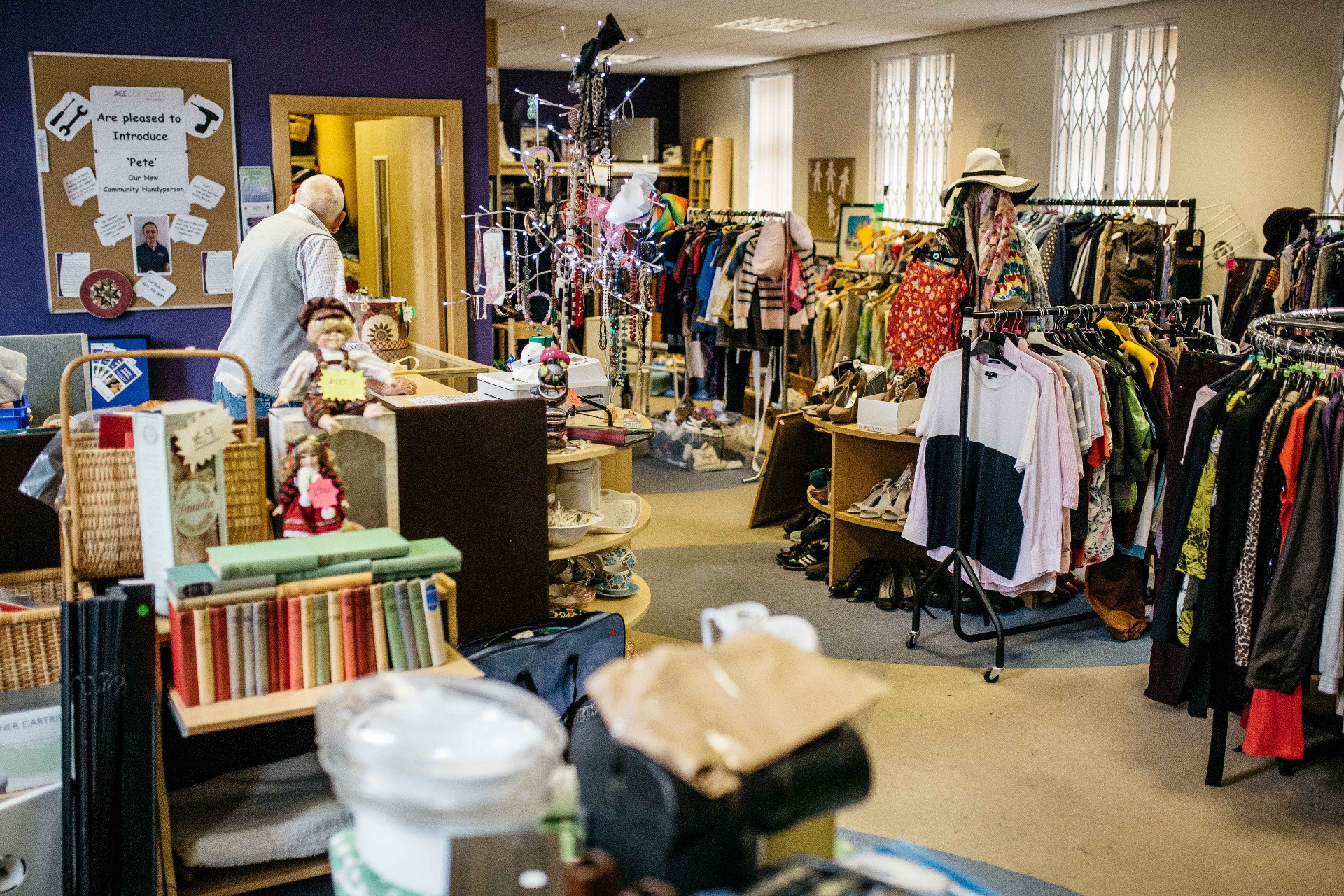 Inside the Boldmere charity shop with rails of clothes, books and bric-a-brac